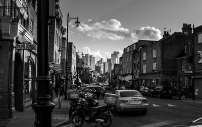 Cars on street by buildings against sky