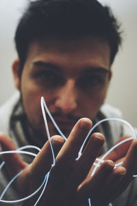 Close-up portrait of man holding string light