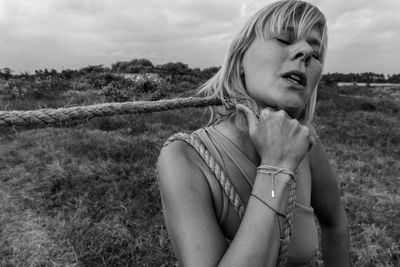 Close-up of woman holding rope while standing on field