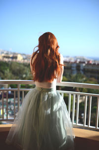 Rear view of woman standing against railing