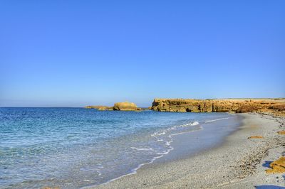 Scenic view of beach against clear blue sky