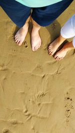 Low section of people standing on sand at beach