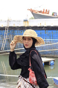 Portrait of woman standing against boat in water