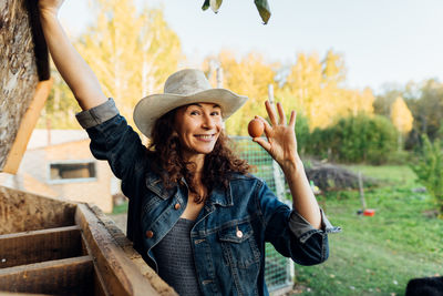 Smiling female farmer takes out a freshly laid egg in the chicken coop.