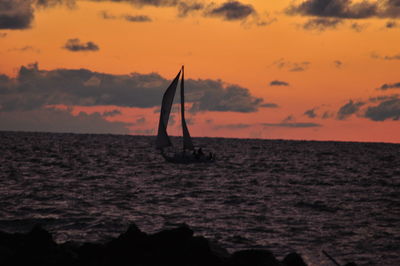 Silhouette man in sea against sky during sunset