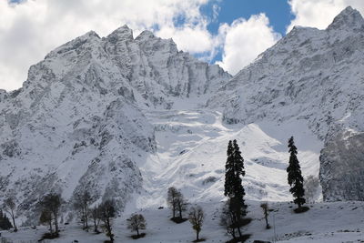 Scenic view of snow covered mountains against cloudy sky