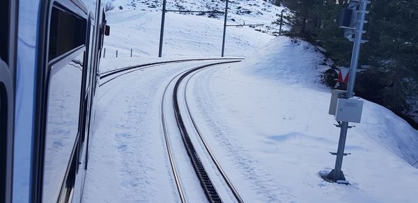 Snow covered railroad track by mountain