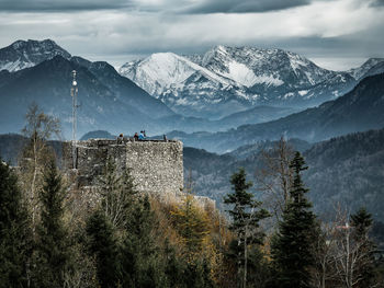 Castle against snowcapped mountains during foggy weather