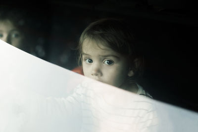 Portrait of girl in car trunk seen through rear windshield