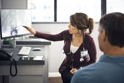 Female doctor explaining report to patient on computer in clinic