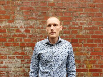 Thoughtful man standing against brick wall