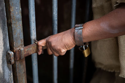 Black woman dressed as a slave, chained with an iron mask on her mouth, holding an iron fence. 