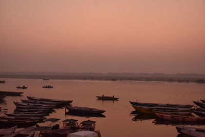 Boats moored in sea against sky during sunset