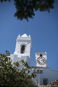 Low angle view of clock and bell tower of church against clear blue sky