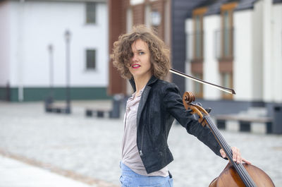 Portrait of young woman with umbrella standing in city