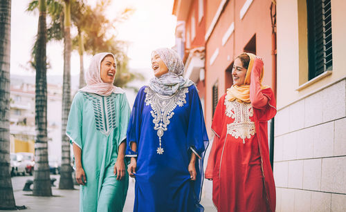 Happy female friends walking by building