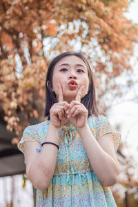 Portrait of young woman standing against tree