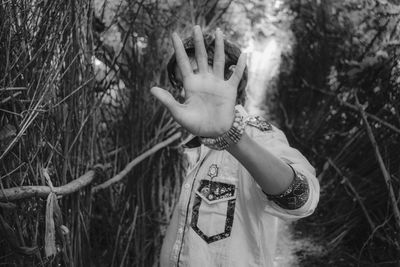 Man gesturing while standing against dried plants