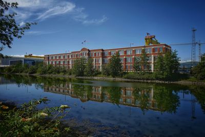 Reflection of buildings in lake against blue sky