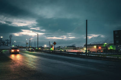 Illuminated road against sky during sunset