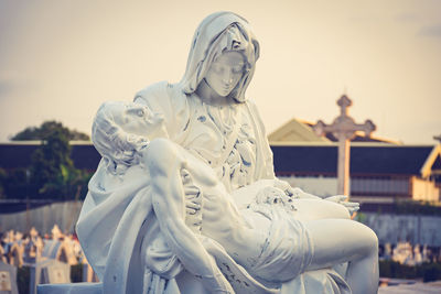 Statue of angel against building in city