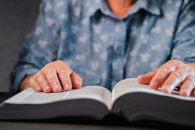 Midsection of woman reading book at home