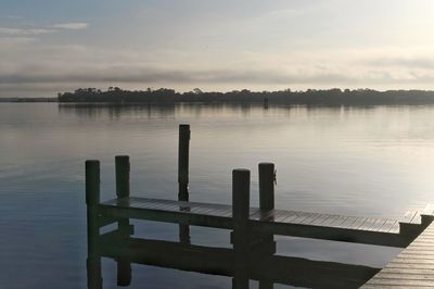 Pier on lake against sky during sunset