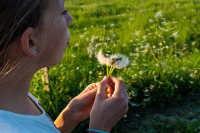 Close-up of girl blowing dandelion