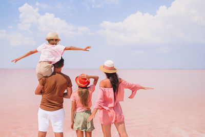 Rear view of people at beach against sky