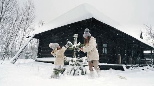  cutie, pretty little girls decorate snow-covered small christmas tree with homemade ice toys