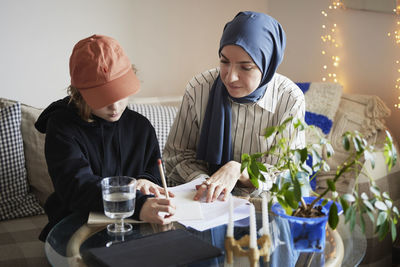 Mother wearing hijab helping son doing homework