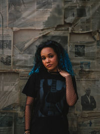 Portrait of young woman standing against wall