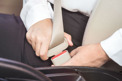 Midsection of man holding smart phone in car