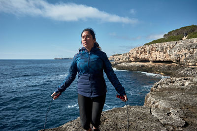 Woman skipping on rock against sea