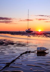 Sailboats moored on sea against sky during sunset