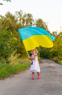 Rear view of woman with umbrella on road