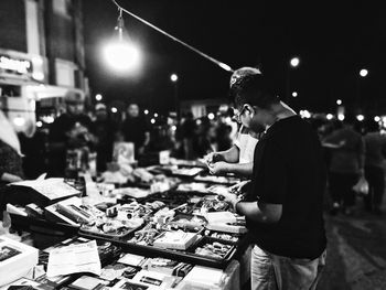 Men standing by illuminated market stall city at night