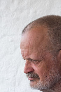 Close-up of thoughtful senior man against white wall