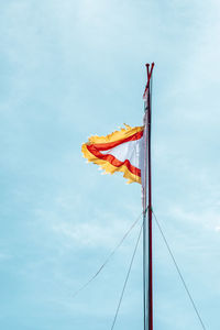 A red-yellow flag flutters against a blue sky in the background