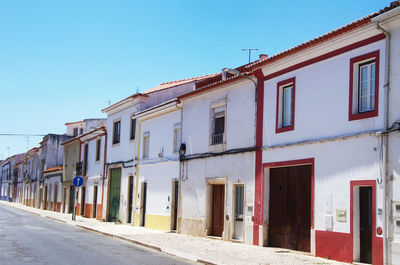 Residential buildings by street against blue sky