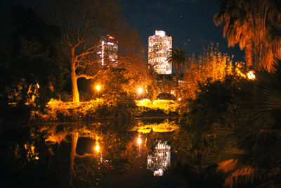 Illuminated building by lake at night