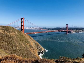 Golden gate bridge over sea against clear blue sky