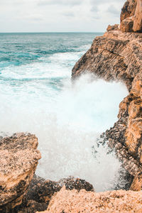 Rock formation on beach against sky