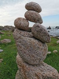 Close-up of stone stack on rock at beach against sky