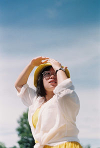 Portrait of young woman standing against sky