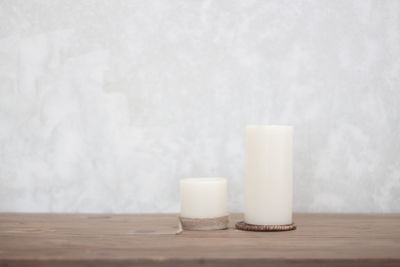 Close-up of white jar on table against wall