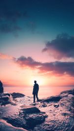 Full length of man standing on shore during sunset