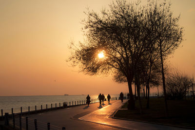 People on beach against sky during sunset