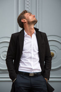 Handsome fashion model posing against closed door