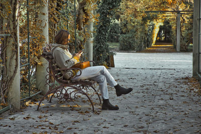 Side view of woman sitting on chair at park